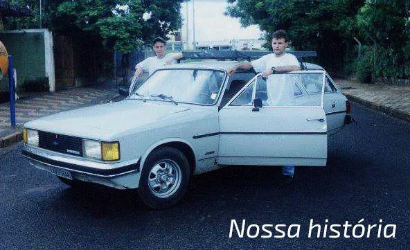 Foto de arquivo do Grupo Edare, legendada Nossa história: dois homens ao lado de uma caminhonete antiga